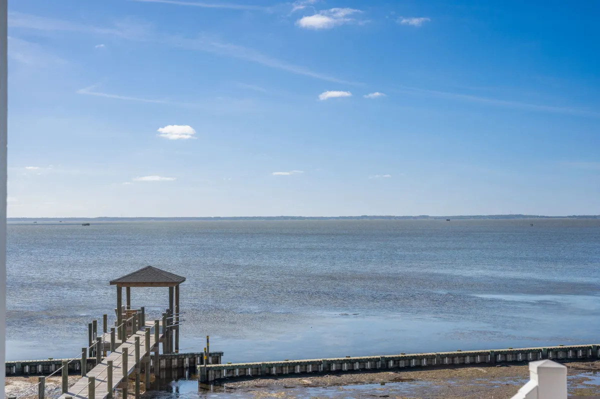 A scenic dock extends over calm water under a wide, open sky, capturing the tranquil beauty of the Sound at sunset. The image highlights direct water access and the kind of serene, picturesque moments visitors can share with their pets at the water’s edge.