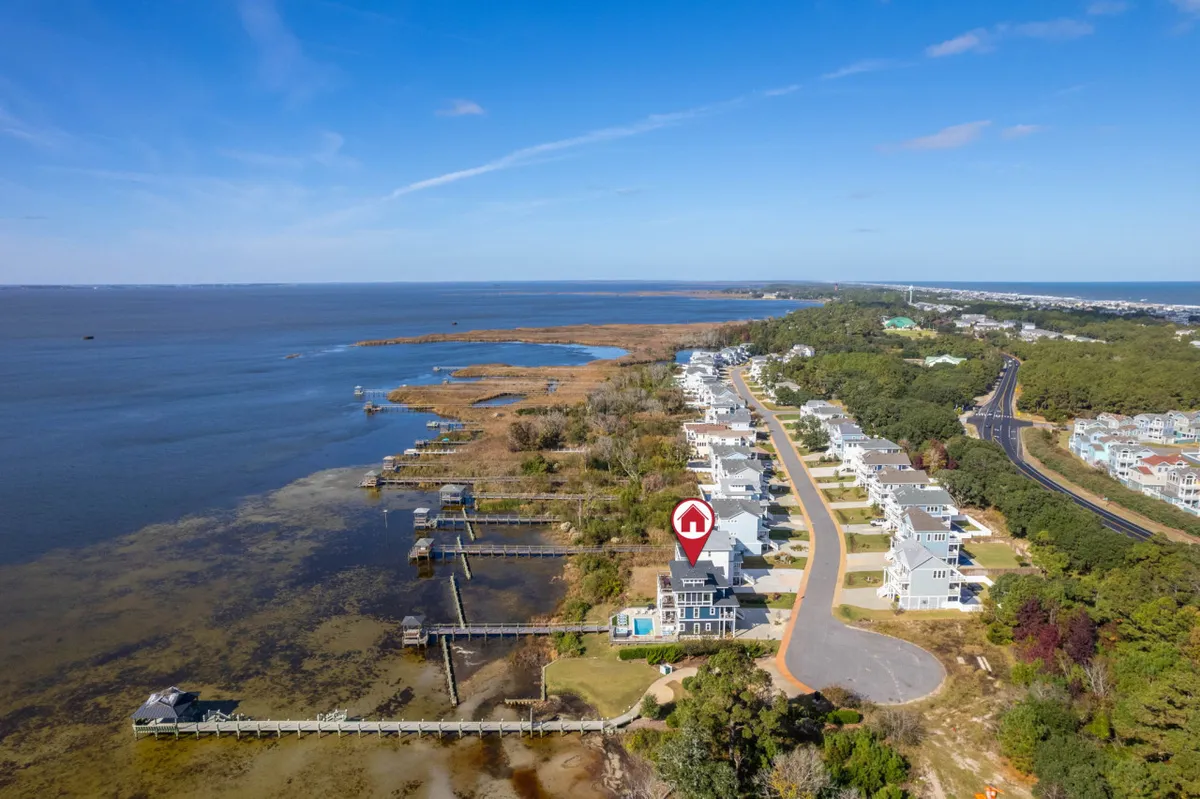 A sweeping view of waterfront properties bordered by marshland, with a roadway leading to the coast. The image captures a tranquil neighborhood landscape that hints at opportunities for exploration, nature walks, and water-based activities.